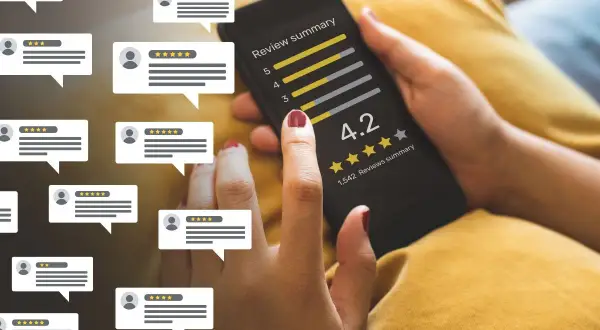 Dłoń trzymająca smartfon z oceną 4.2 i gwiazdkami, otoczona dymkami z opiniami.