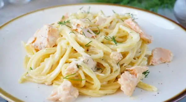 Spaghetti mit Lachs und Dill in cremiger Sauce auf einem Teller.