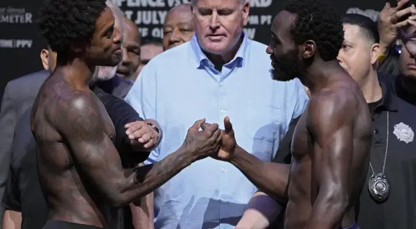 Terence Crawford and Errol Spence Jr. shake hands before their fight, surrounded by officials and a crowd.