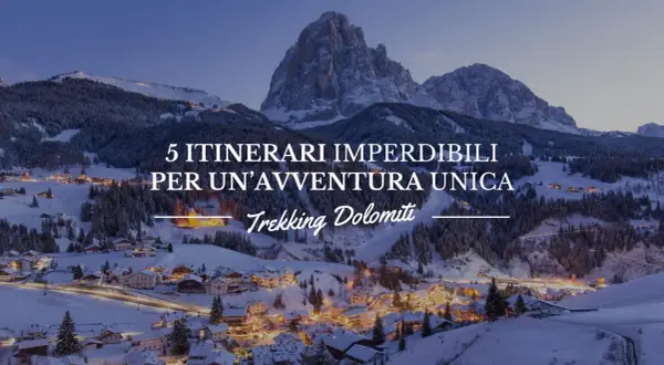 Paesaggio invernale con villaggio illuminato e montagne innevate. 5 itinerari imperdibili per un'avventura unica: Trekking Dolomiti.