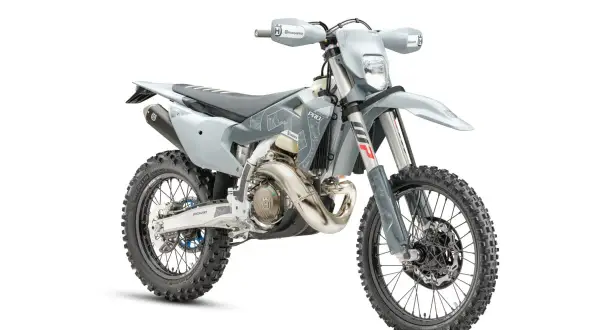 Szary motocykl Husqvarna z oponami terenowymi na białym tle.