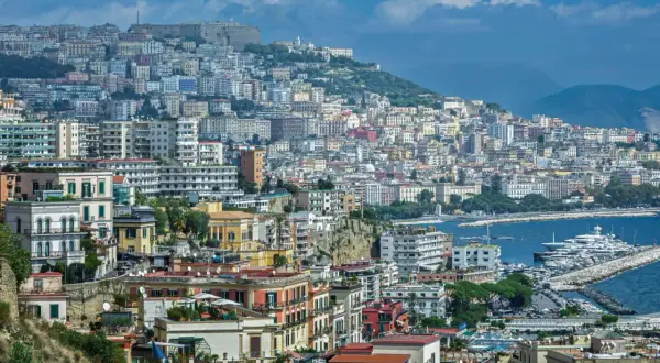 Panorama di Napoli con case colorate, il Vesuvio sullo sfondo e yacht nel porto. Come si dice in napoletano? "Napule è!