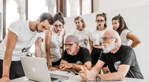 Stefano Guindani e un gruppo di giovani analizzano un progetto al computer, concentrati e seri.