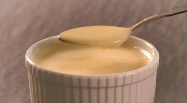 Cremige Vanillesauce, frisch zubereitet, auf einem Löffel. Perfekt zum vanillesauce selber machen.