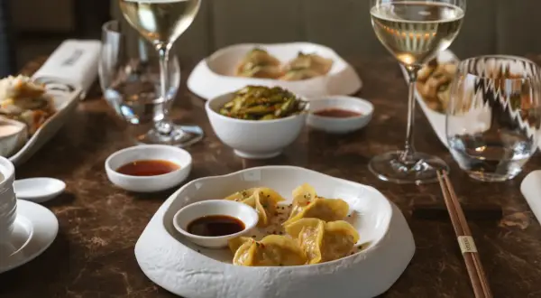 Ristoranti stellati Milano: un'esperienza culinaria con ravioli dorati, edamame e vino bianco.