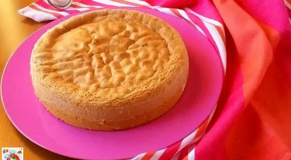 Gâteau Pan di Spagna, parfait pour une recette génoise moelleuse. Servi sur une assiette rose avec un torchon coloré.
