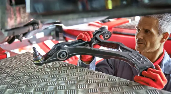 Mechanik w czerwonych rękawiczkach prezentuje nowy wielowahacz do samochodu.