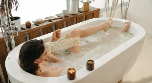 Relaks w wannie z naturalnymi kosmetykami. Półka nad wanną inspiracje: świece, zioła, szczotka do kąpieli.