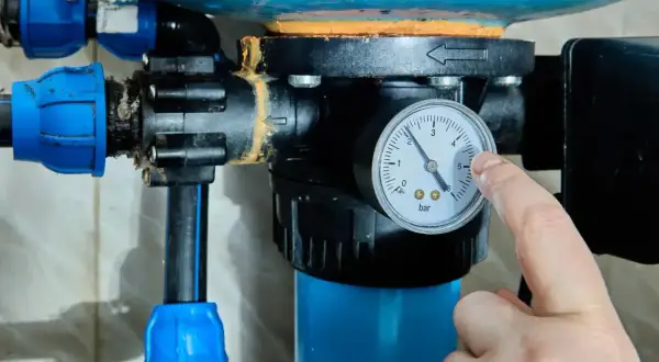 Palec wskazuje manometr przy hydroforze, pokazując ciśnienie. Dowiedz się, jak odpowietrzyć hydrofor, by działał sprawnie.
