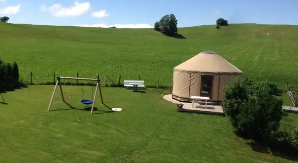 Une yourte confortable vous attend pour un séjour paisible en pleine nature, location yourte Jura. Balançoire et bancs invitent à la détente.
