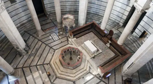 Interno della Torre di Pisa: vista dall'alto del battistero ottagonale, colonne imponenti e mosaici sul pavimento.