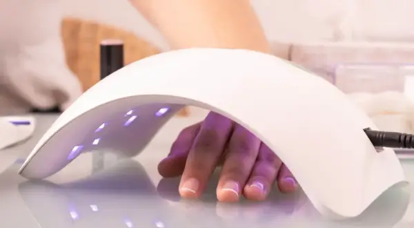 Dłoń pod lampą LED 48W, utwardzanie żelu. Ile utwardzać żel w lampie led 48w? Czas zależy od produktu.