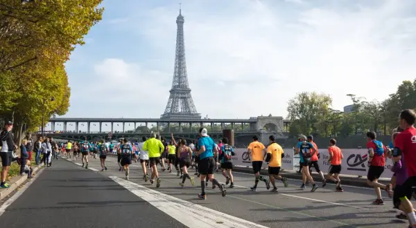 Course de marathon à Paris, avec la Tour Eiffel en arrière-plan. L'allure marathon 3h20 est visée par ces coureurs déterminés.