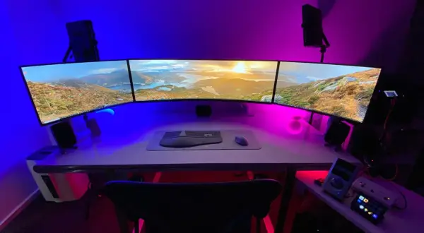 Nowoczesne stanowisko z trzema monitorami, klawiaturą i myszką. Dowiedz się, jak podłączyć monitor do laptopa, by stworzyć podobny setup.