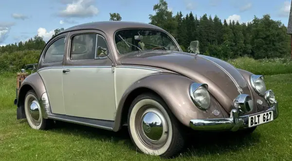 En tvåfärgad bubblan bil står på en gräsmatta.