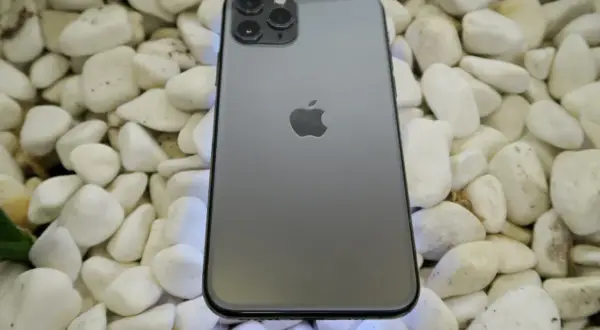 Szary iPhone 11 Pro leży na białych kamieniach. To urządzenie iPhone niedostępne, ale wciąż piękne.