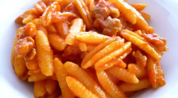 Malloreddus alla campidanese, pasta sarda con sugo di pomodoro e salsiccia, un piatto ricco e saporito.