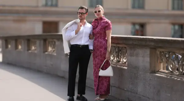 Elegancka para na spacerze, inspiracja, jak się ubrać do teatru. Mężczyzna w białej koszuli i czarnych spodniach, kobieta w różowej sukni.