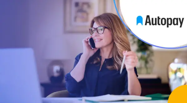 Kobieta w okularach rozmawia przez telefon, pracując przy laptopie. Rozwiązania autopay mobility ułatwiają jej codzienne życie.