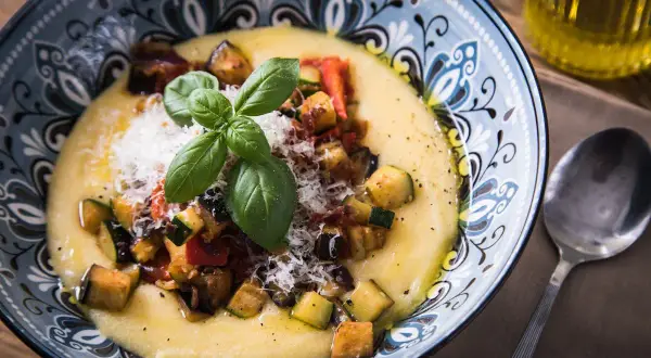 Cremige Polenta mit gebratenem Gemüse, Parmesan und Basilikum. Was ist Polenta? Ein herzhaftes Gericht aus Maisgrieß.