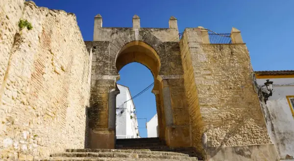 Antigua puerta de acceso a Medina Sidonia, con escalinata de piedra y cielo azul. Merece la pena visitar Medina Sidonia.