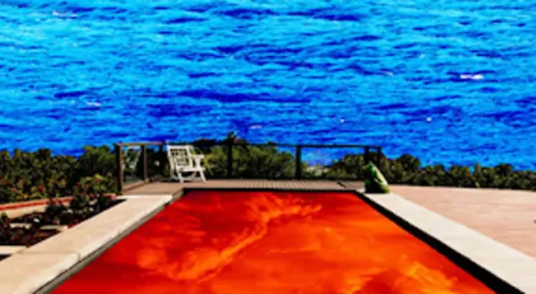Płonący basen z wodą w kolorze czerwonym, jak na okładce Californication Red Hot Chili Peppers, na tle błękitnego morza.