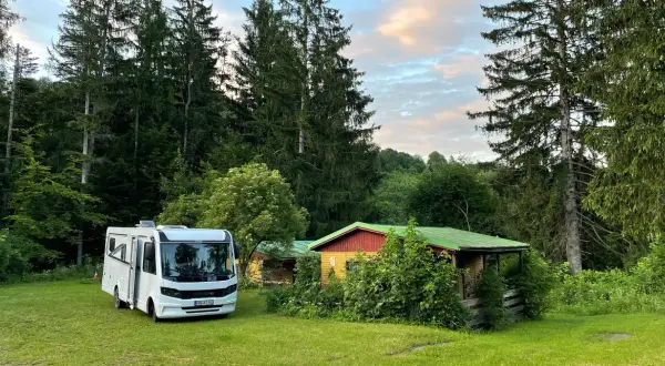 Wohnmobil neben bunten Hütten im Wald, ein idyllischer Ort nahe Banská Štiavnica.