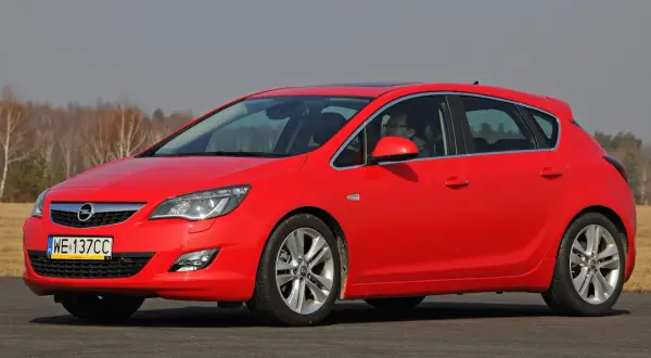 Czerwona Opel Astra na drodze. Kierowca za kierownicą. Jaki akumulator do tego modelu?