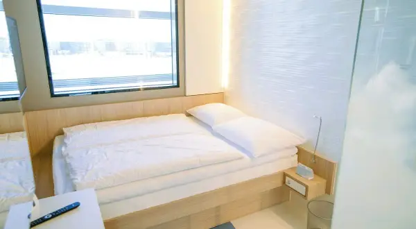 Nowoczesny pokój hotelowy z łóżkiem, oknem i pilotem.