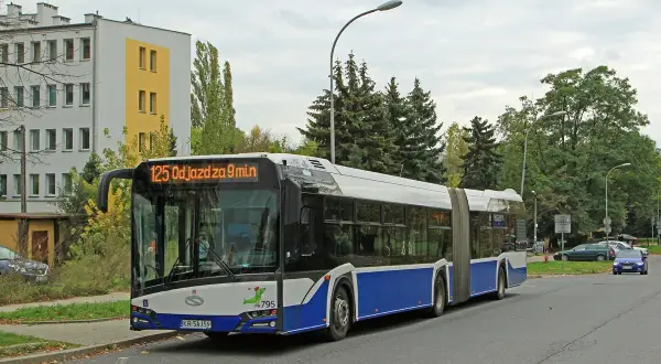 Autobus linii 125 odjeżdża za 9 minut. Długi, przegubowy pojazd stoi na przystanku obok budynku mieszkalnego.