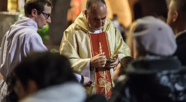Kapłan udziela Komunii Świętej. Wierni przyjmują Ciało Chrystusa, co jest ważnym momentem po spowiedzi, gdy grzech ciężki został wyznany.
