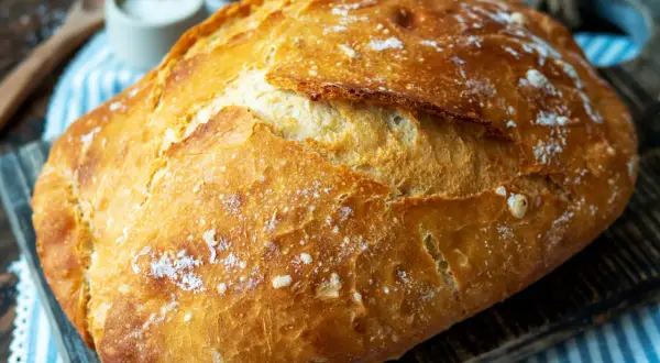 Ein frisch gebackenes, knuspriges Brot liegt auf einem Holzbrett. Perfekt für einfaches Brot backen.