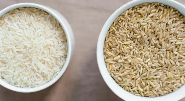Zwei Schalen Reis: eine mit hellem Basmati oder Jasmin Reis, die andere mit braunem Reis.