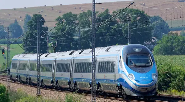 Pendolino na tle krajobrazu z sianem na wzgórzu.