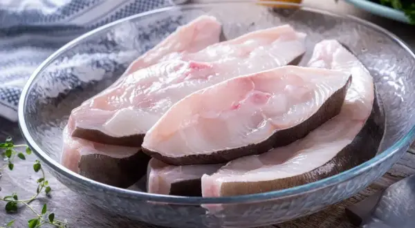 Świeże kawałki halibuta ryby w szklanej misce, gotowe do przygotowania.