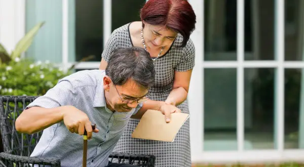 Una donna aiuta un uomo con bastone a rialzarsi. La speranza è che la paraplegia si può guarire, con supporto e cure.