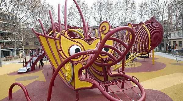 Un parque infantil con forma de dragón amarillo y rojo en Usera. ¡Un lugar genial que ver en Usera para los niños!