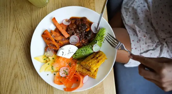 Assiette colorée avec carottes, avocat, maïs, fromage frais et viande en sauce. Une délicieuse alternative au riz pour un repas sain et savoureux.
