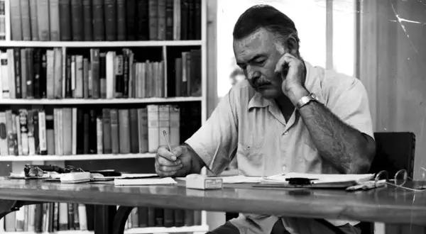 Ernest Hemingway pisze, myśląc o tym, komu bije dzwon. Streszczenie jego myśli widać w skupieniu na twarzy.