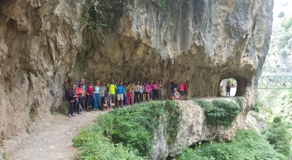 Grupo de excursionistas posa en la Ruta del Cares, superando la dificultad del terreno rocoso y los túneles.