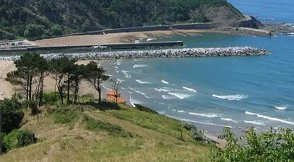 La playa mas cercana a Logroño, con olas rompiendo en la arena y un rompeolas protegiendo el puerto.