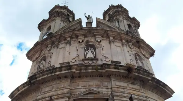 La imponente fachada de la iglesia de la Virgen Peregrina se alza bajo un cielo nublado, con sus torres y estatuas de piedra.