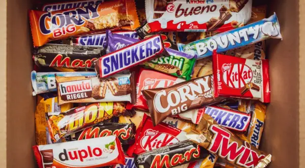 Pudełko pełne słodyczy: Snickers, Mars, Twix, Bounty, Kinder Bueno, Corny, Duplo i inne popularne polskie marki słodyczy.