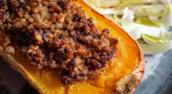 Moitié de courge butternut farcie, une recette savoureuse avec une garniture dorée et croustillante, servie avec une salade fraîche.