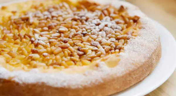 Deliciosa tarta de piñones, cubierta con azúcar glas, lista para disfrutar.