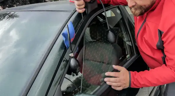 Mężczyzna używa narzędzia do otwierania drzwi, gdy zatrzaśnięte kluczyki w samochodzie jak otworzyć.