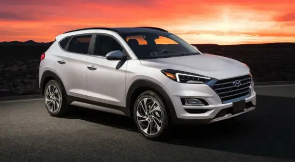 Un Hyundai Tucson blanco con un motor potente, listo para la aventura al atardecer en un paisaje desértico.