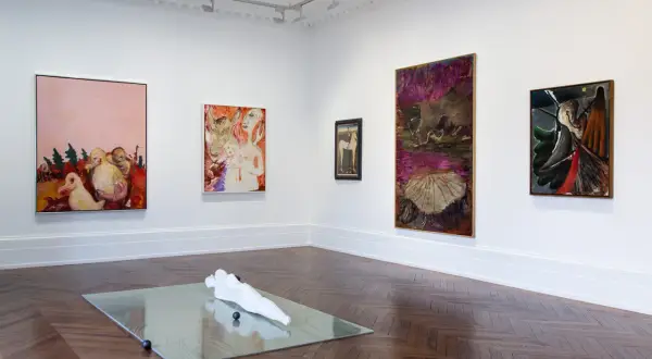 Artistic display at Michael Werner Gallery featuring abstract paintings and a sculpture on a mirrored surface.