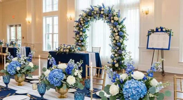 Elegancka sala weselna z niebieskimi akcentami. Kwiatowe łuki i dekoracje stołów tworzą magiczną atmosferę.
