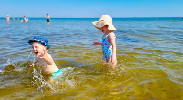 Dzieci bawią się w wodzie na plaży, jednej z urokliwych miejscowości blisko Gdańska.